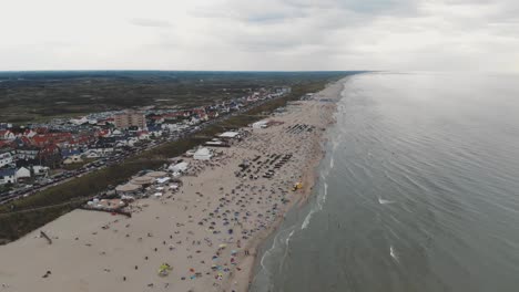 Drone-footage-of-a-crowded-beach-along-the-coast-of-Zandoort,-Netherlands