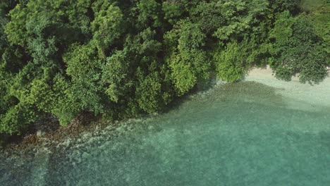 Aerial-birds-eye-view-medium-trucking-right-drone-shot-of-a-small-deserted-tropical-island-beach-with-clear-turquoise-water-in-South-east-Asia