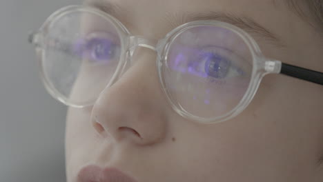 Closeup-of-a-kid-with-glasses-gazing-at-a-screen