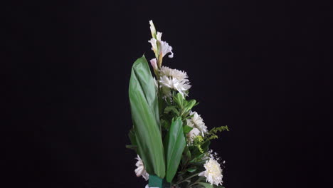 Kleines-Tropisches-Blumenarrangement-Für-Begräbnisse,-Das-Sich-Auf-Schwarzem-Hintergrund-Dreht