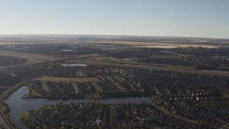 aerial-drop-fly-over-cookie-cut-residential-detached-luxury-homes-low-rise-apartments-many-ponds-all-replica-of-the-town-of-Inverness-Scottland-in-a-township-outside-of-Calgary-Alberta-Canada-1-2