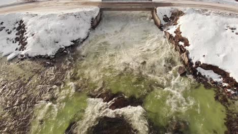 Turbulent-water-from-Dam's-floodgate,-streaming-down-icy-cold-cascade---static-Bird's-eye-view-aerial-shot