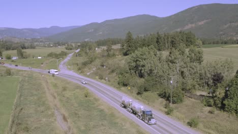 Mountain-valley-highway-freeway-interstate-following-a-silver-white-generic-fuel-double-tanker-truck-gas-carrier-trailed-by-a-white-RV-motorhome-towing-a-vehicle-on-a-clear-hot-summer-day-MH1-2