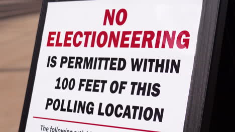 No-Electioneering-is-Permitted-Within-100-Feet-of-this-Polling-Location-Sign-with-Person-Walking-in-Background,-woman