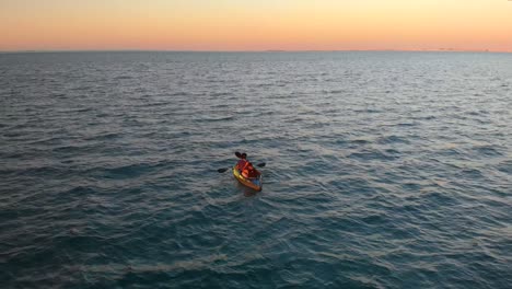 Ein-Paar-Kajak-In-Reflektierenden-Tiefen-Ozeangewässern-Während-Des-Herrlichen-Orangefarbenen-Sonnenuntergangs