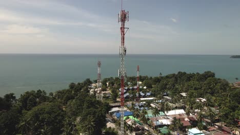 Aerial-drone-ascending-shot-of-telecommunications-tower-on-a-tropical-Island-in-Thailand-with-ocean-in-background