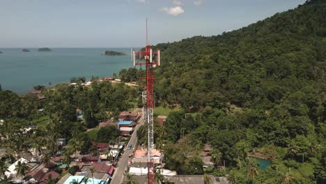 Aerial-drone-birds-eye-view-shot-of-4G-and-5G-telecommunications-tower-in-a-small-coastal-village-on-a-tropical-Island-in-South-East-Asia-with-ocean-and-Islands-in-the-background