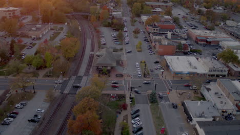 Aerial-view-of-main-street-and-train-tracks-in-downtown-Kirkwood,-Missouri-at-sunset-in-Autumn-with-a-tilt-down