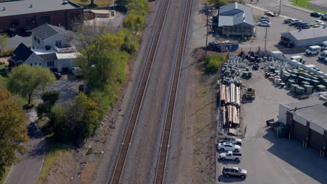 Aerial-view-of-train-tracks-in-small-town-neighborhood-with-tilt-up-to-follow-the-track-to-the-horizon