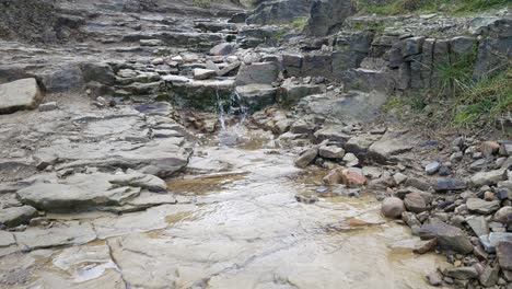 Rough-broken-wet-stone-pathway-cascading-rainfall-overcast-Autumn-hiking-trail