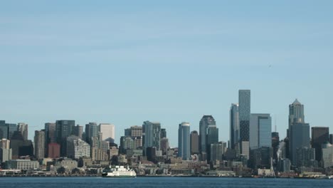 Ferry-Cruising-On-Calm-Water-With-Waterfront-Buildings-In-The-Background---View-From-West-Seattle,-Washington---static-shot