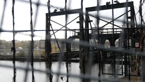 Rainy-Anderton-canal-industrial-boat-lift-waterway-through-fenced-security-gates-dolly-left