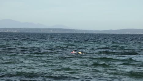 Person-Swimming-At-Alki-Beach-In-Seattle,-Washington-On-A-Bright-Weather---wide-shot,-slow-motion