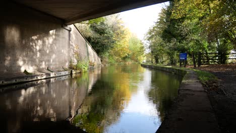 Under-old-canal-bridge-waterway-sunny-autumn-reflections-on-water-with-rainfall-drizzle