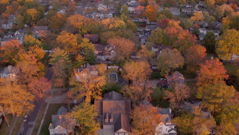 Aerial-flyover-beautiful-houses-and-colorful-trees-in-Kirkwood,-Missouri-at-golden-hour-in-Autumn