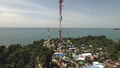 Aerial-drone-descending-shot-of-4G-and-5G-telecommunications-tower-on-a-tropical-Island-in-Thailand-with-ocean-in-background