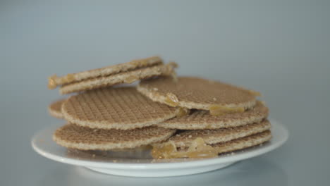 Hand-grabbing-a-single-cookie-from-a-pile-of-stroopwafels,-a-typical-Dutch-treat