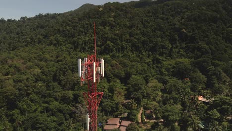 Aerial-drone-slow-clockwise-orbit-shot-of-telecommunications-tower-on-a-tropical-Island-in-Thailand-with-jungle-behind