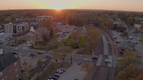 Aerial-push-towards-city-hall-over-train-tracks-in-small-town-at-sunset-in-Autumn