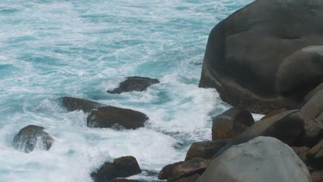 close-up-of-waves-crashing-on-a-stack-of-rocks-at-the-beach-in-Tayrona-Park,-Colombia