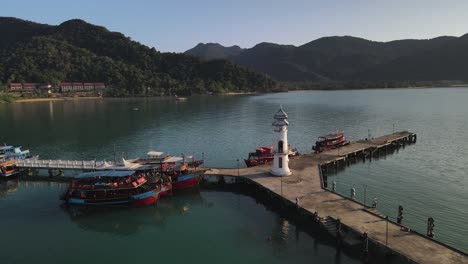 Slow-aerial-orbit-shot-of-Bang-Bao-pier-in-Koh-Chang,-Thailand-with-sun-hitting-the-lighthouse