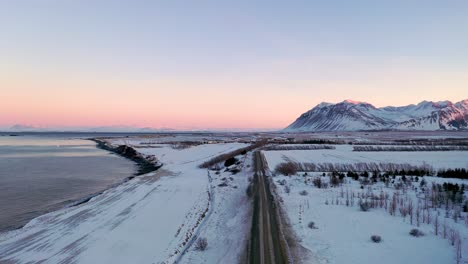 Maravilloso-Paisaje-Nevado-Junto-Al-Mar-En-Una-Puesta-De-Sol-En-Islandia,-Invierno---Dron-Ascendente