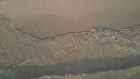 Aerial-top-view,-medium-shot-of-ocean-small-tropical-wave’s-break-on-a-beach