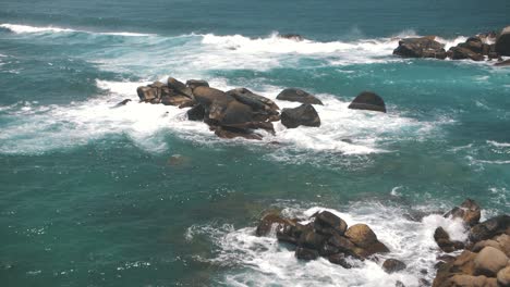 Wellen,-Die-Gegen-Einen-Felsstapel-Im-Blauen-Meer-Des-Tayrona-Parks,-Kolumbien,-Schlagen