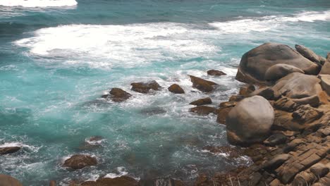 waves-crashing-against-stack-of-rocks-on-a-cliff,-at-Tayrona-Park,-Colombia