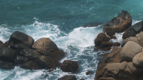 beautiful-slow-motion-shot-of-waves-crashing-against-the-rocks-at-the-beach-of-Tayrona-Park,-Colombia