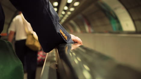 Traveling-on-a-horizontal-escalator-on-the-London-Underground,-suit-sleeve-and-hand-visible-of-male-rider
