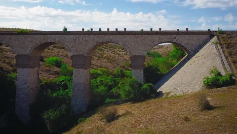 Drone-dolly-in-camera-movement-up-on-an-old-yellow-stone-viaduct-bridge,-part-of-the-Medgidia-Tulcea-railway