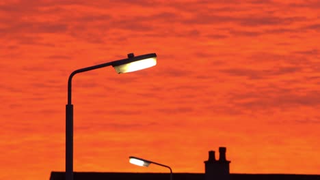 Unglaublicher-Orangeroter-Himmel-Bei-Sonnenuntergang-Und-Silhouette-Beleuchteter-Straßenlaternen