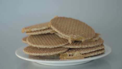 Pile-of-stroopwafels,-a-typical-dutch-cookie,-lying-on-a-white-plate---panning-dolly