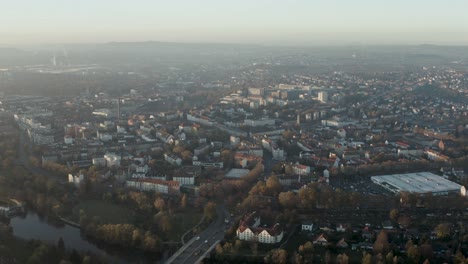 Drohnenaufnahme-Der-Stadtlandschaft-Von-Kassel-In-Schönem,-Weichem-Sonnenlicht-Und-Mit-Nebel-Bedeckt