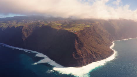 Aerial:-Gigantic-coastline-of-Madeira-Island-with-crashing-waves-and-lighting-landscape