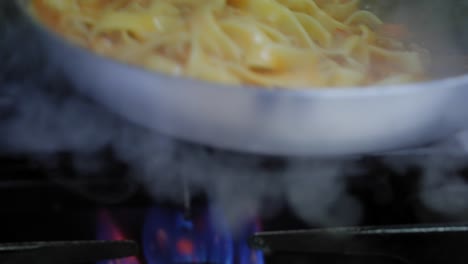 Slow-motion-close-up-of-tossing-tagliatelle-noodles-and-Bolognese-sauce-in-a-frying-pan