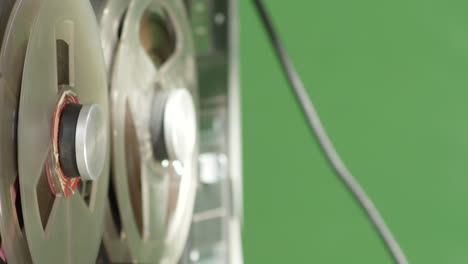 Tape-recorder-playing-magnetic-deck,-closeup-side-view,-green-screen-background