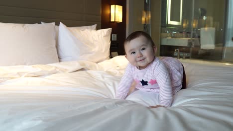 Schönes-Babymädchen-Krabbelt-Am-Abend-Nach-Dem-Check-in-Auf-Dem-Weißen-Hotelzimmerbett