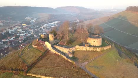 Aerial-approaching-Weibertreu-Castle,-Weinsberg,-and-the-beautiful-vineyards-on-the-hills