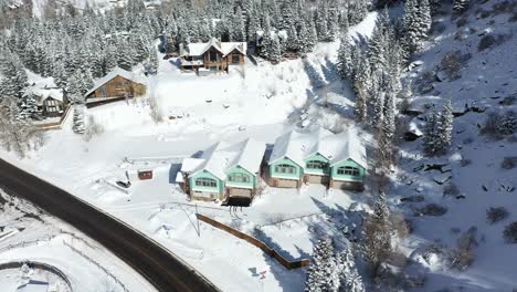 Aerial-view,-wooden-houses-and-cottages-in-sunny-snowy-winter-landscape-of-Ouray-small-mountain-town-in-Colorado-USA