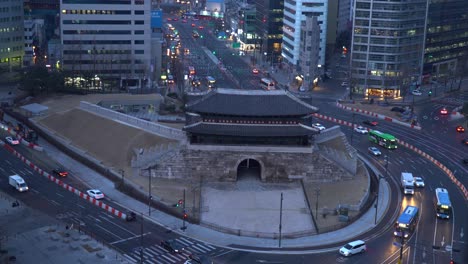 Buses-and-cars-fast-passing-Road-intersection-in-front-of-Sungnyemun-gate-in-Seoul-city,-South-Korea