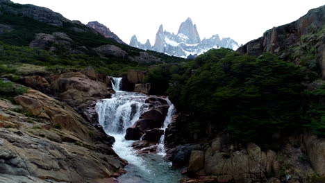 Aerial---Mount-Fitz-Roy-behind-a-waterfall,-Patagonia,-Argentina,-wide-shot