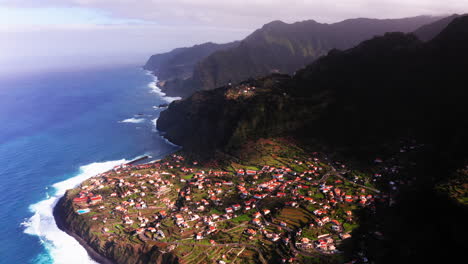 Aerial-flight-over-small-village-of-Ponta-Delgada-with-houses-located-on-hilltop-with-beautiful-coastline-and-blue-ocean-during-sunlight
