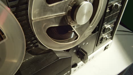 Tape-recorder-started-by-hand,-stopping-and-rewinding-magnetic-deck,-closeup-view