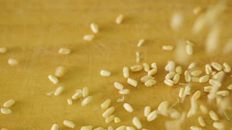 Close-up-of-dried-grains-of-wheat-spilling-onto-a-wooden-table-in-slow-motion