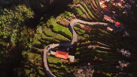 Aerial-top-down-shot-of-cars-driving-on-curvy-rural-road-during-sunlight