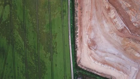 Top-down-aerial-view-of-beautiful-green-field-next-to-gravel-pit,-Essenbach,-Bavaria