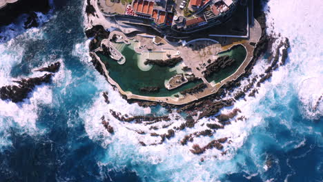 Descending-aerial-view-of-empty-natural-pool-at-Porto-Moniz-during-sunlight