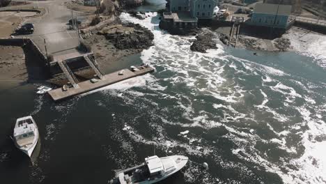 Aerial-pull-back-shot-of-rapidly-flowing-water-at-Cohasset-Harbor